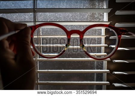 Woman's Hand Holding   Shortsighted Or Nearsighted Eyeglasses With Dust Blinds Inside A Window, Dust