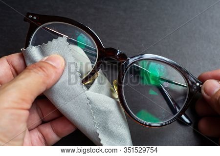 Woman's Hands Cleaning Shortsighted Or Nearsighted Eyeglasses By Microfibre Cleaning Cloths, On Blac