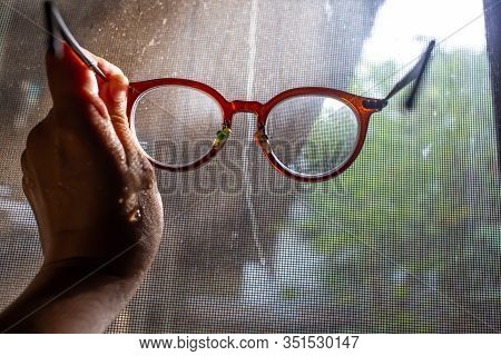 Woman's Wet Hand Holding   Shortsighted Or Nearsighted Eyeglasses With Dust And Dirty Mosquito Wire 