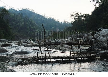 Scenario Of Little River And A Foot Bridge Beside A Range Of Mountains