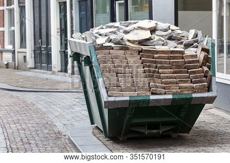 Neat Industrial Skip Parked On The Clean Sidewalk Full Loaded With Bricks And Rubble In Dordrecht In