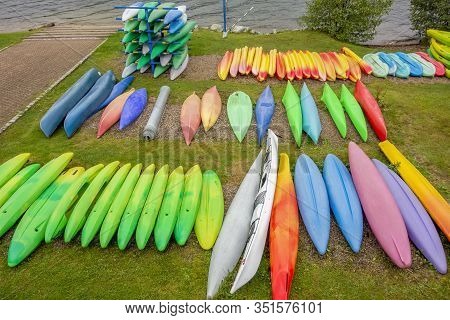 High Angle Riparian Scenery Showing Lots Of Colorful Canoes Lying Upside Down On Grassy Ground Seen 