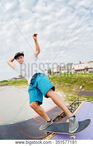 Portrait Of A Young Skateboarder Doing A Trick On His Skateboard On A Halfpipe Ramp In A Skate Park 