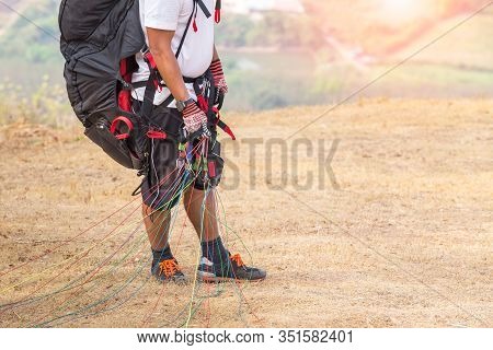 Paraglider On The Ground. Paragliders With Full Flight Equipment Look On Soaring Another Paragliders