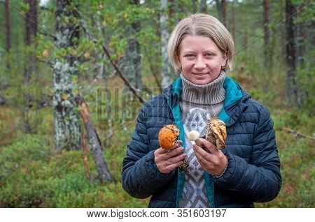 A Sincerely Smiling Woman Demonstrates The Mushrooms Collected In The Forest. Picking Up Fresh Organ