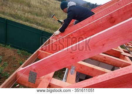 A Man Fastens Two Wooden Beams With A Self-tapping Screw, Installing Wooden Rafters On The Roof.