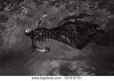 Beautiful Photo Of Woman Lying In The Water In Wet Dress. Woman In A Magnificent Red Dress Lies On T