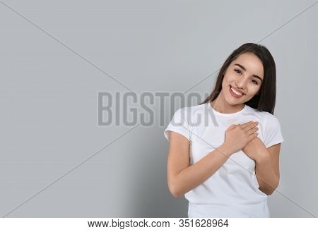 Beautiful Grateful Woman With Hands On Chest Against Light Grey Background. Space For Text