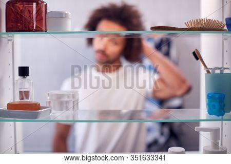 View Through Bathroom Cabinet Of Man Getting Ready For Work In The Morning