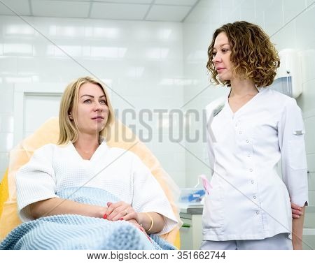 Woman Wearing Disposable Medical Bathrobe Being At Consultation In Cosmetology Clinic. Attractive Fe