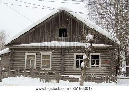 Old Wooden One-story House On A Background Of A Winter Landscap. Outdated Russian Urban Architecture