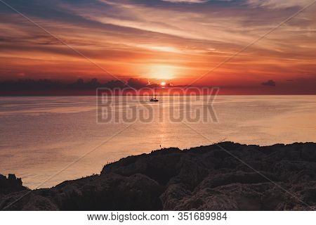 Beautiful Colorful Sunrise At The Sea With Dramatic Clouds, The Sailing Boat And Sun Shining