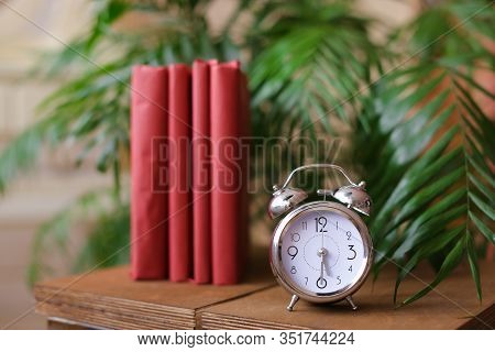 Red Stylish Photo Albums Stnding Near Clock And Houseplant On Table.