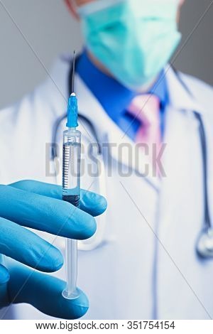 Close Up View Of Medical Syringe In Rubber Blue Glove Dressed Hand, Man Chest In White Medical Robe 
