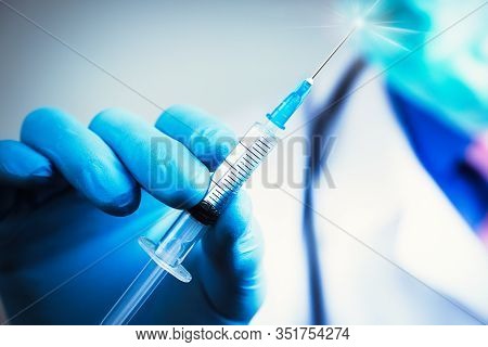 Close Up Hand Of Doctor In Blue Latex Glove And Medical Gauze Mask With Transparent Syringe. Health 