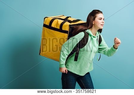 Pretty Delivery Woman Running While Carrying Thermo Backback On Blue Background