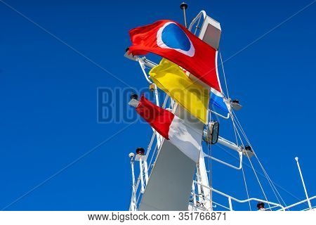 Carnival Cruise Line, Quarantine And Pilot Flags Flying In Strong Winds On A Blue Day On A Cruise Sh