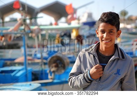 Mahdia, Tunisia - December 27, 2019: Portrait Of A Smiling Teenager At The Fishing Port, With Fishin
