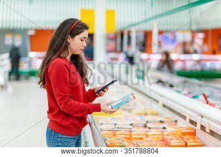 A Young Caucasian Woman Scans The Qr Code On The Package With A Semi-finished Product. Concept Of Mo