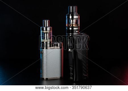 Electronic Cigarettes Or Vaping Devices On Black Background. Toned Light