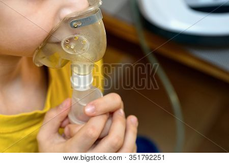 Child Makes Inhalation At Home With Nebulizer On Out Of Focus Background. Example Of Combating Respi