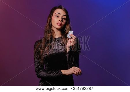 Brunette Woman In Black Velvet Dress Showing Multicolored Chips, Posing Against Coloful Background. 