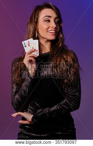 Brunette Woman In Black Velvet Dress Showing Two Playing Cards, Posing Against Coloful Background. G
