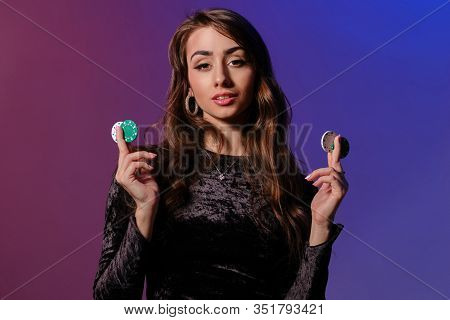 Brunette Woman In Black Velvet Dress Showing Multicolored Chips, Posing Against Coloful Background. 