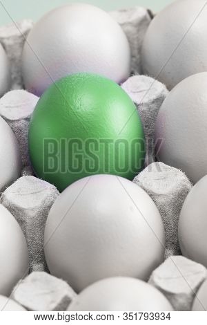 One Green Egg Among Many White Eggs In The Box, Close-up. Upstart And Leader, Vertical Photo. Symbol