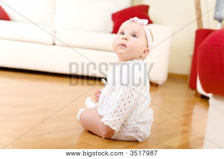 Meisje van de baby gezeten op een hardhouten vloer
