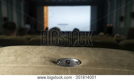 Watching Films. Blurred Movie On The Big Screen In The Cinema And Chair With Nomber..