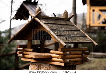 Birdhouse On A Tree Hanging From A Branch. Wooden Birdhouse Made Of Small Logs. Birdhouse On Blurred