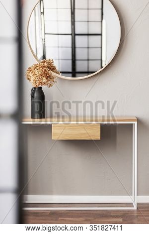 Elegant Round Mirror In Wooden Frame Above Fancy Console Table With Flowers In Vase In Trendy Bedroo