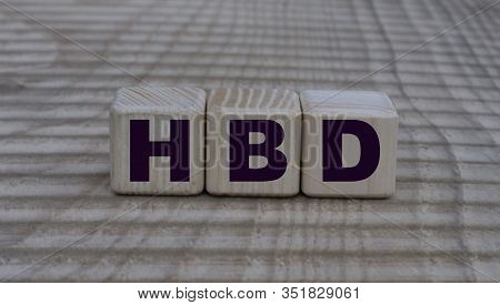 The Concept Of The Word Hbd On Cubes On A Wooden Background With Vertical Stripes