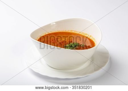 Beef Goulash Soup With Tongue. A White Oval Plate With Red Soup Stands On A White Background.