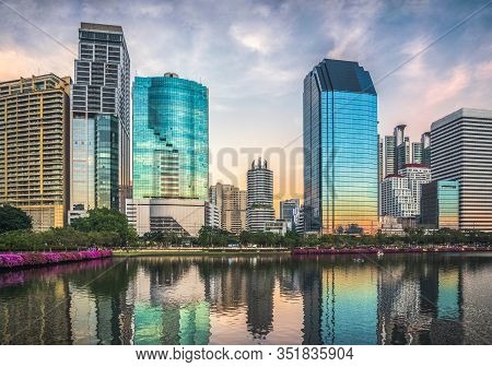 Skyscrapers Reflected In A Lake At Twilight. Benjakiti Park In Bangkok, Thailand