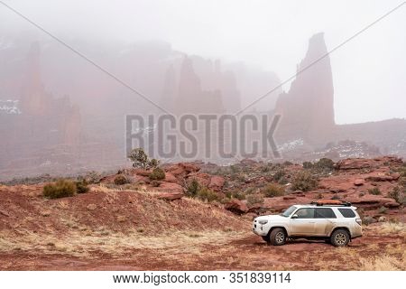 Moab , UT, USA - February 9, 2020:  Toyota 4runner SUV (2016 trail edition, stock vehicle) with recovery ladders on roof racks on a 4x4 trail in winter conditions with Fisher Towers in background.