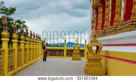 Woman In Sarong Walking Along Wall Of Wat In Pak Nam Pran Pranburi Thailand.