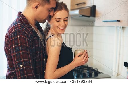 Careful Man Embracing His Caucasian Girl With Freckles And Red Hair While Drinking A Coffee In The K