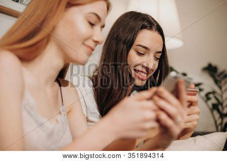 Charming Caucasian Girl With Red Hair And Freckles Is Texting With Her Brunette Friend Sitting On A 