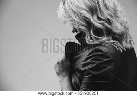 Beautiful Young Woman With Blond Hair Standing In Profile. She Holds The Collar Of Her Leather Jacke
