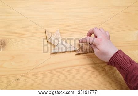 Girl Collects A Wooden Tangram Puzzle On A Wooden Table.