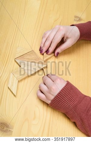 Girl Collects A Wooden Tangram Puzzle On A Wooden Table.