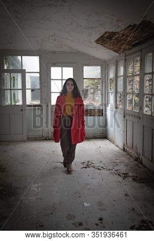 Young Beautiful Woman Dressed In Red Walking In An Abandoned And Colapsing Room