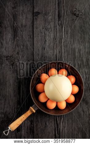 Ostrich Egg, Selective Focuse, Surrounded By Chicken Eggs In An Old Cast-iron Skillet, Which Is Stan