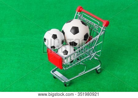 Soccer balls in shopping cart on green foorbal field