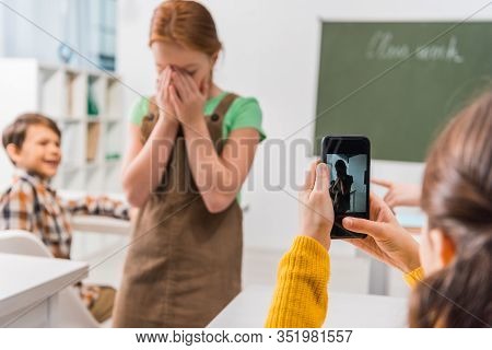 Selective Focus Of Schoolgirl Taking Photo Of Classmate, Cyberbullying Concept