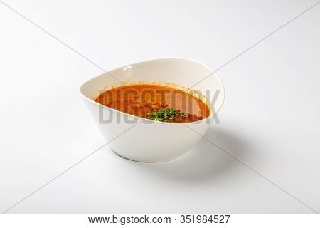 Beef Goulash Soup With Tongue. A White Oval Plate With Red Soup Stands On A White Background