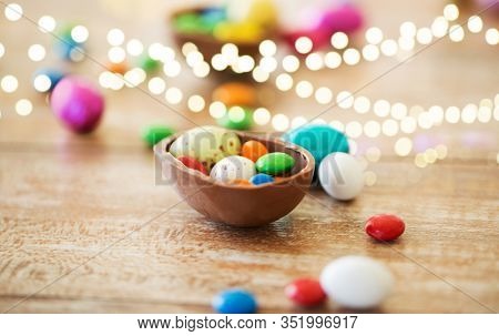 easter, junk-food, confectionery and unhealthy eating concept - close up of chocolate egg and candy drops on table