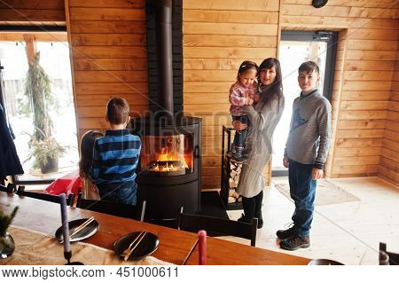 Mother And Four Kids In Modern Wooden House Against Table And Fireplace, Spending Time Together In W